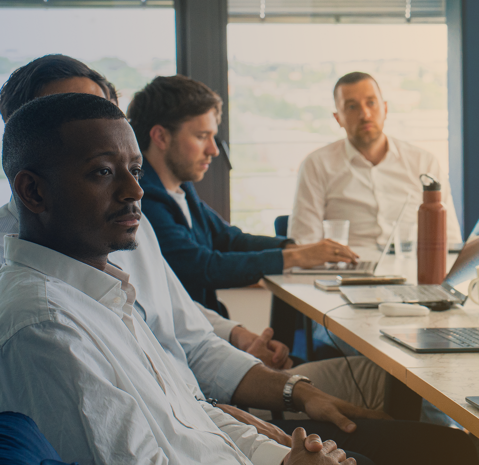 Plusieurs hommes derriere un bureau en réunion avec des ordinateurs