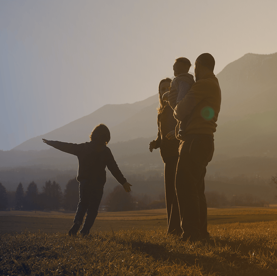 une famille avec un couple et deux enfant dans un champs au couché du soleil